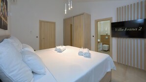 Een hotelkamer met een bed, twee houten kasten, een televisie en een badkamer die door een open deur zichtbaar is.