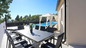 Een terras met zwembad, buitenmeubels en een tafel met stoelen.