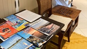 A staircase with a black railing, a wooden chair with a woven backrest, and a table with travel magazines.