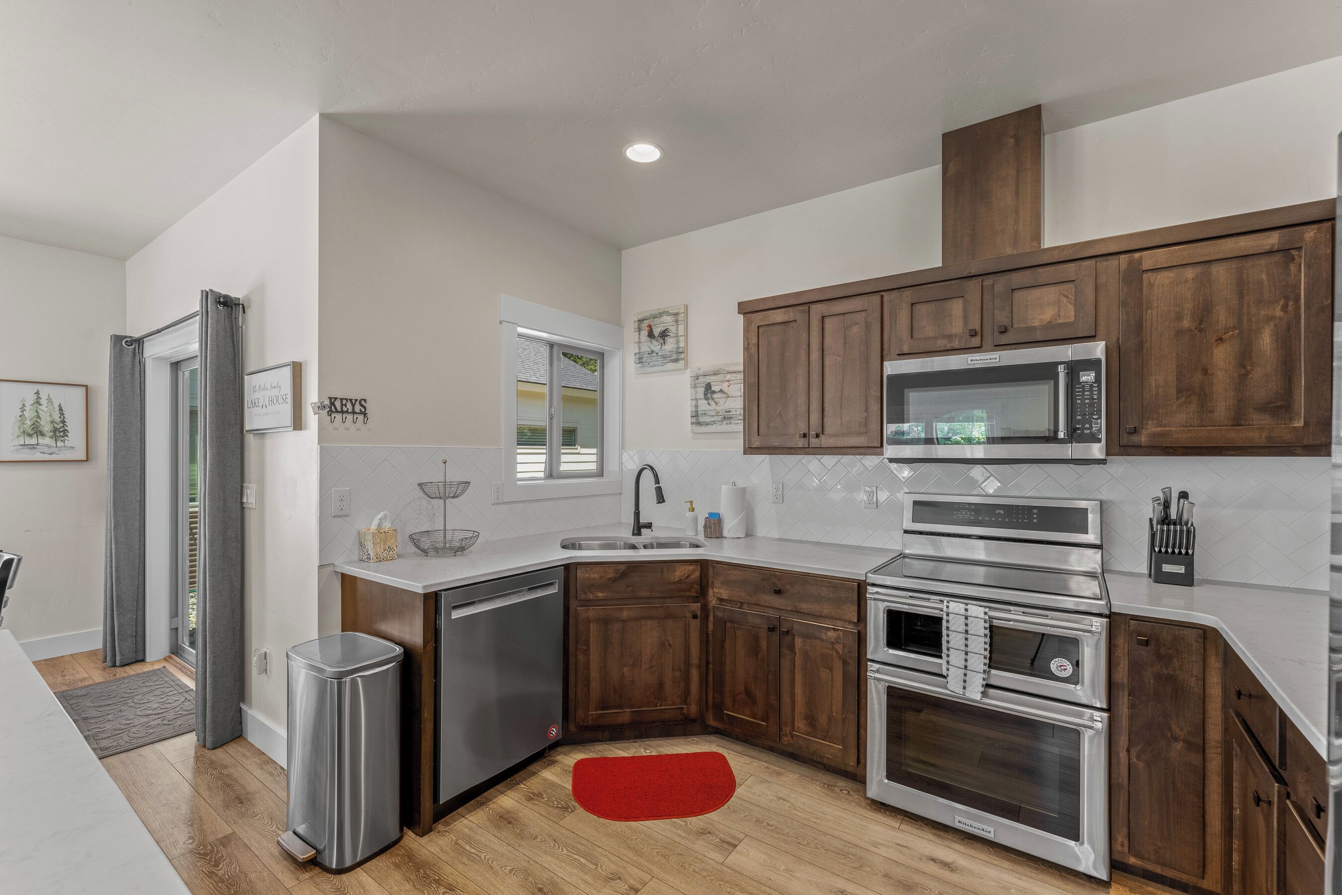 Una cocina moderna con armarios de madera, electrodomésticos de acero inoxidable y una alfombra roja.