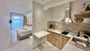 A modern hotel room with a large bed, a small kitchenette, and a bathroom.