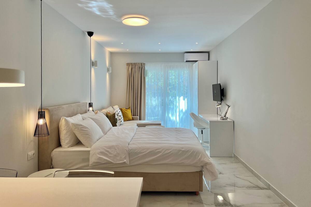 A modern hotel room with a large bed, bedside tables, a desk, and a TV.