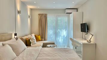 A modern hotel room with a large bed, a desk, a television, and a window with curtains.