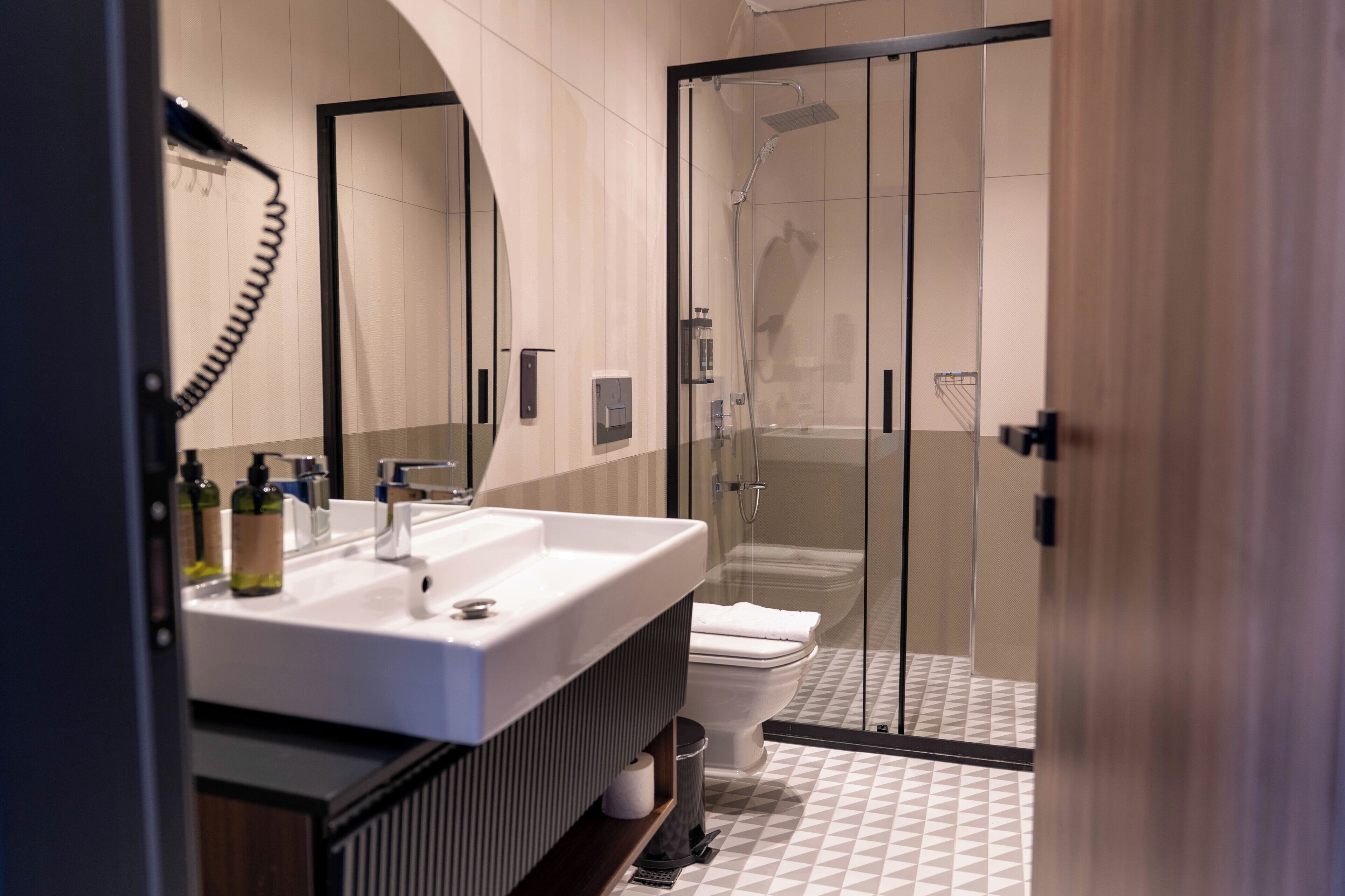 A modern bathroom with a glass shower enclosure, a white sink, and a toilet.