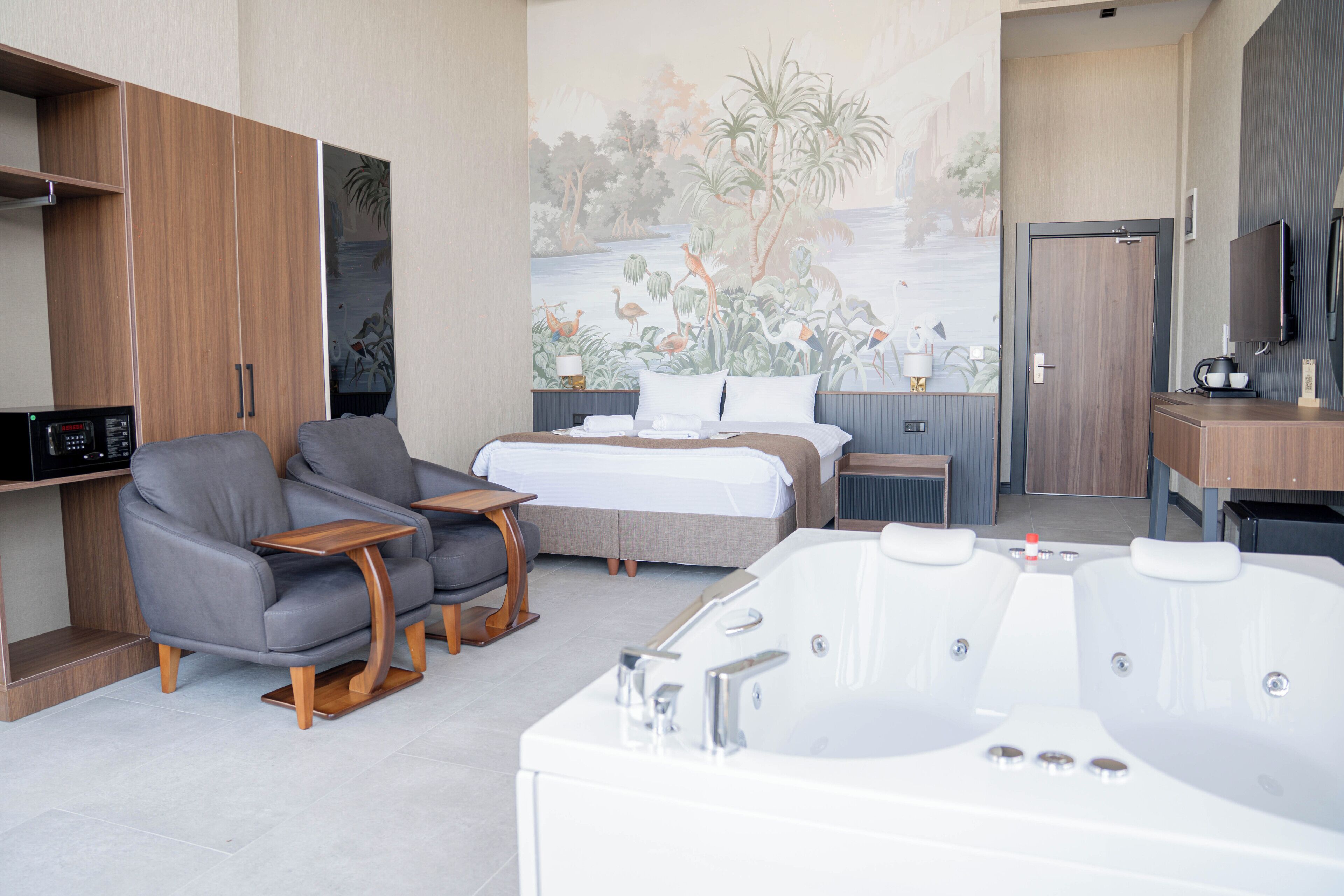 Una habitación de hotel moderna con cama, sofá, escritorio, televisor y un mural grande.