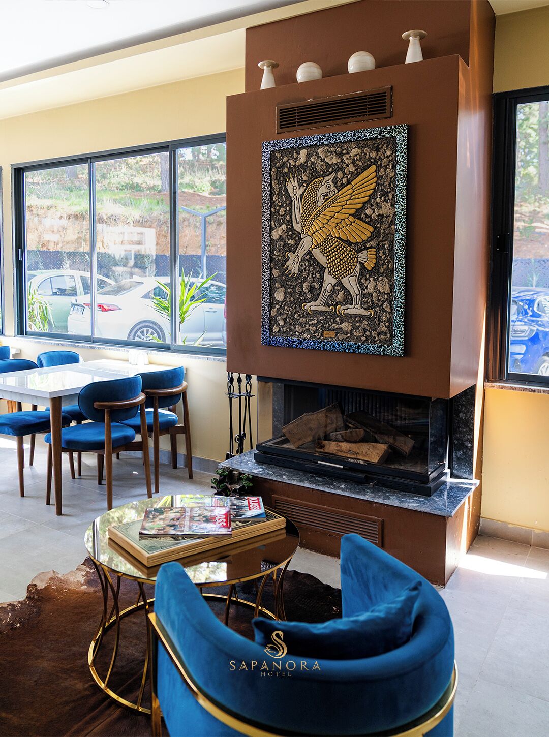 A modern interior with a fireplace, blue chairs, and a dining table.