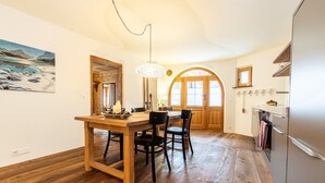 Eine Küche mit Holzboden, einem Esstisch mit Stühlen, einem Kühlschrank und einem großen Fenster mit Bergblick.