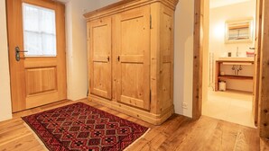 Ein Flur mit einem Holzschrank, einem Teppich mit Muster und einem Badezimmer inklusive Waschbecken und Spiegel.