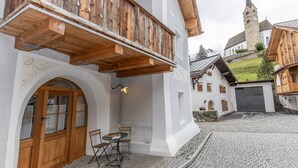 Ein traditionelles europäisches Gebäude mit einem hölzernen Balkon, einer Steintreppe und einem Kopfsteinpflasterhof.
