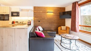 A modern living space with a kitchen, a sofa, a coffee table, and a view of the outdoors. - Simply Morzine - Apartment le Sautaillet (Morzine)