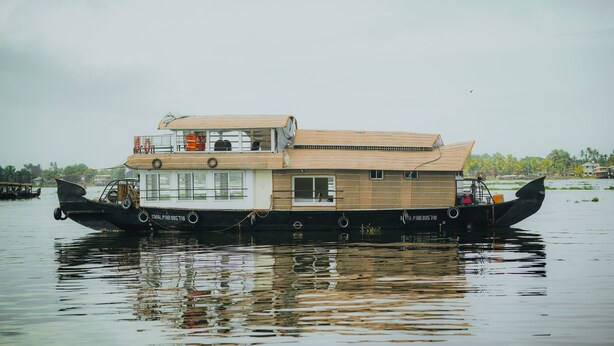 A houseboat with a flat roof, multiple decks, and a visible kitchen area.