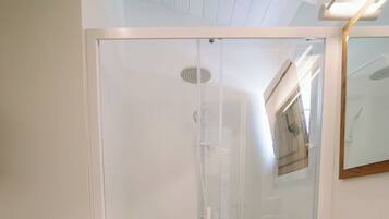 A modern bathroom with a glass shower enclosure, a white sink, and a wooden vanity.