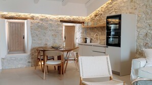 Cuina compacta amb paret de pedra, mobles de fusta i forn integrat.