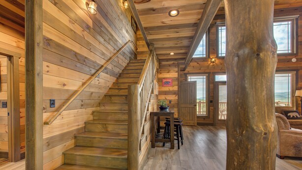 A wooden staircase leading to a loft area with a view of the outdoors.
