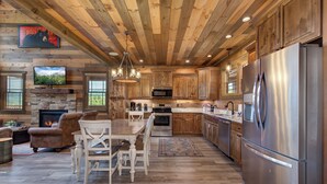 A spacious kitchen with wooden cabinets, stainless steel appliances, and a dining area with a fireplace.
