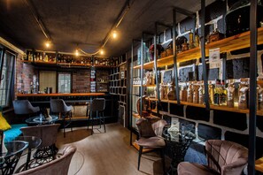 Een bar met zitplaatsen, flessen op de planken en een bakstenen muur.