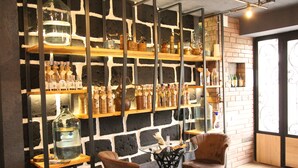 Zona de bar con estantes llenos de botellas, una mesa de cristal y dos sillas.