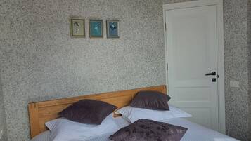 Un dormitorio con cabecera de madera, una cama con ropa de cama a rayas y tres cuadros en la pared.