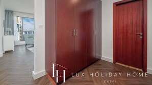 A spacious room with a large wardrobe, a door, and a view of the city. - LUX The JBR Central Suite (Dubai)