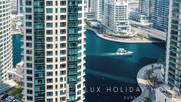 A high-rise building with a view of a waterway and other buildings. - LUX The JBR Central Suite (Dubai)