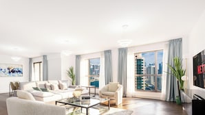 A modern living room with a sofa, armchairs, a coffee table, and a TV. - LUX The JBR Central Suite (Dubai)