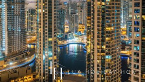 A high-rise hotel with multiple floors, a waterfront view, and illuminated balconies. - LUX The JBR Central Suite (Dubai)