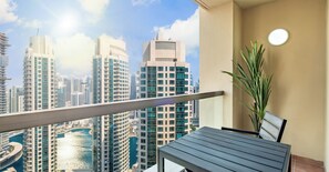 Un balcón con vista al horizonte de Dubái, una mesa y una planta en maceta.