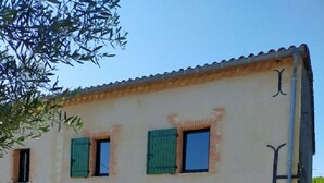 A two-story building with a beige facade, green shutters, and a small garden area with flowers. - . Special PMR. Near one of France's most beautiful villages. Views (Brousse)