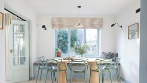 Zona pranzo con tavolo apparecchiato per sei, circondato da sei sedie, una finestra con vista sul verde e un lampadario.