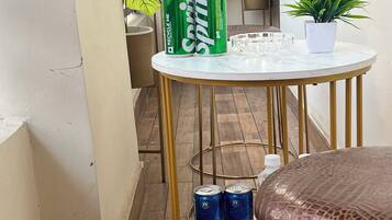 A round table with a white marble top and gold legs, accompanied by two cans of Sprite and a potted plant.