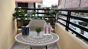 Un balcon avec une table ronde, deux chaises et des plantes en pot.