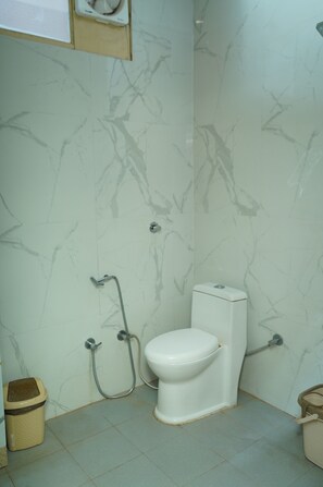 Un baño con inodoro, ducha y cubo de basura.