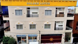 Un immeuble à plusieurs étages dont la partie supérieure, de couleur jaune, porte l’inscription « GOLDEN LOTUS ».