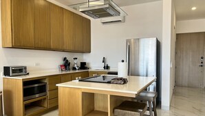 Una cocina moderna con armarios de madera, un refrigerador de acero inoxidable, un microondas integrado y una isla central con taburetes.