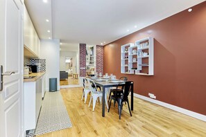 A modern dining area with a wooden floor, a dining table set for six, and a brick accent wall. - Superb Apartment - Beaubourg - Le Marais (Paris)