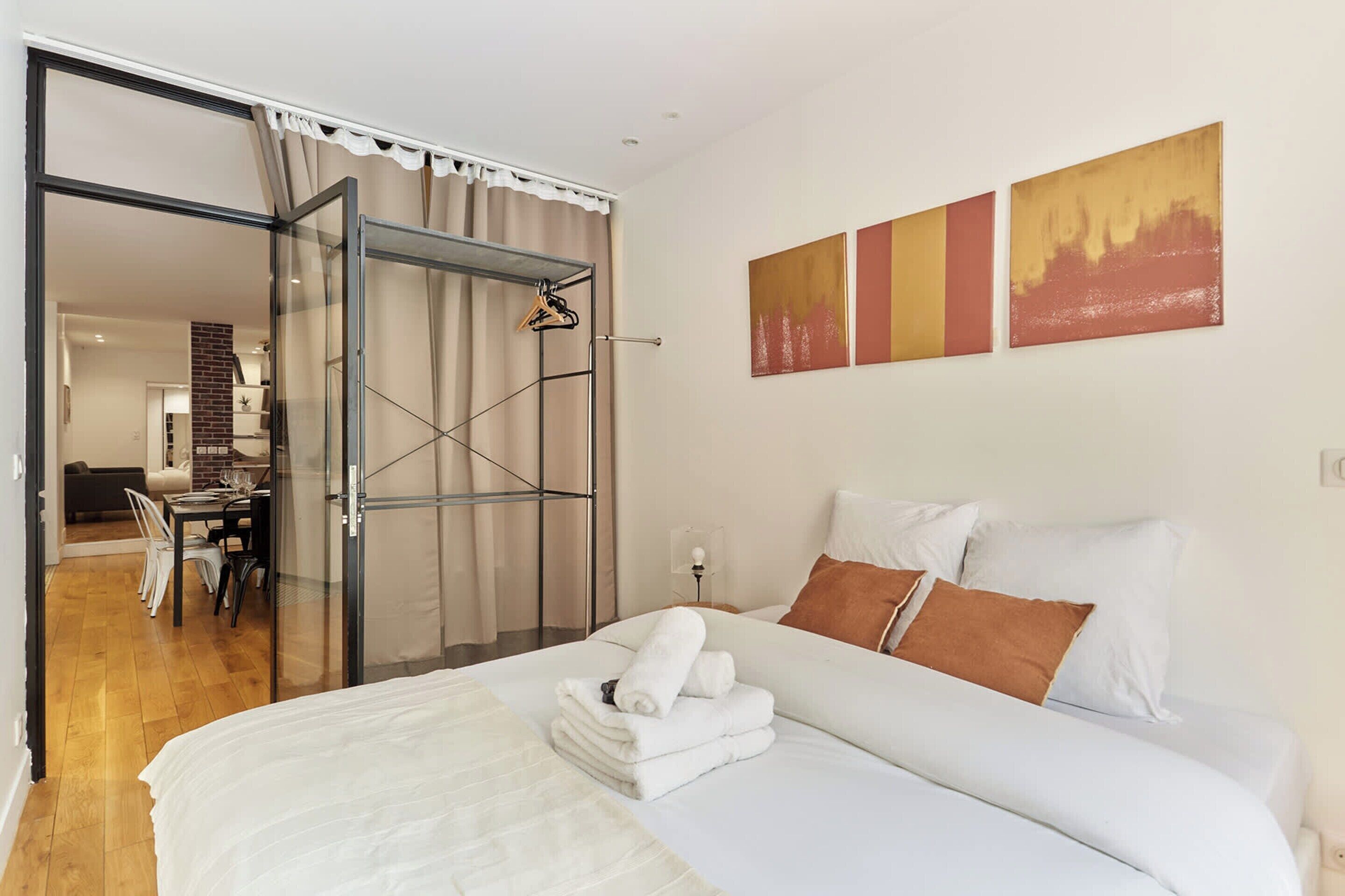 A hotel room with a bed, a dining area, and a sliding glass door leading to a bathroom.