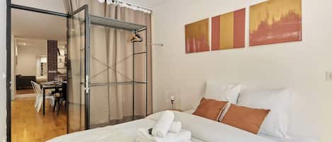 A hotel room with a bed, a dining area, and a sliding glass door leading to a bathroom.