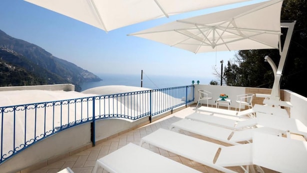 A terrace with white lounge chairs and umbrellas, overlooking a mountainous landscape. - VILLA DEI SRLS in Positano (Positano)