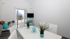 A modern, minimalist room with a white table, chairs, and potted plants. - VILLA DEI SRLS in Positano (Positano)