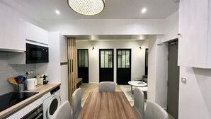 A modern kitchen with a built-in microwave, a washing machine, and a dining area with a wooden table and chairs.