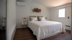 Une chambre avec un grand lit, une table de chevet, un climatiseur fixé au mur et une fenêtre.