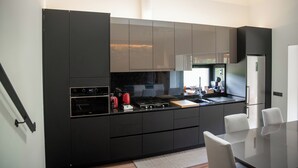 Une cuisine moderne dotée d’appareils électroménagers intégrés, un coin repas avec une table en verre et une vue sur l’extérieur.