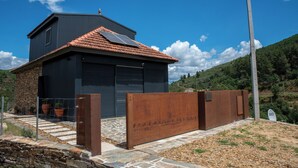 Une maison moderne avec une façade en pierre, un grand portail de garage et une clôture en métal.