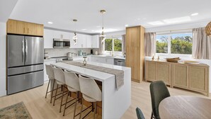A modern kitchen with a central island, stainless steel appliances, and a view of greenery outside. - Coastal retreat!   West end steps to beach! (Sanibel)