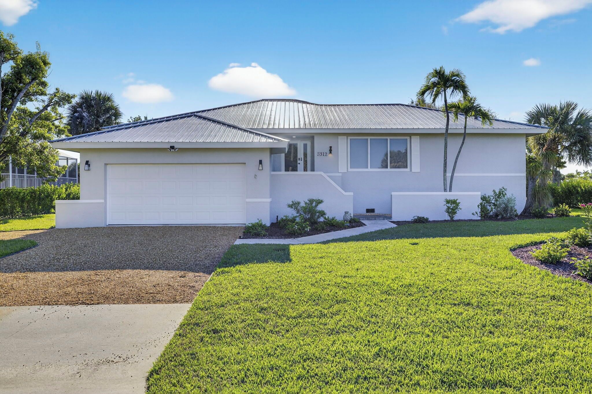 Ein Bungalow mit Garage, überdachter Veranda und gepflegtem Rasen.