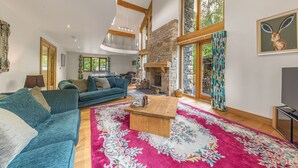 A spacious living room with a large blue sofa, a wooden coffee table, and a stone fireplace.