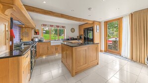 A spacious kitchen with wooden cabinets, a central island, and a large window overlooking a garden.