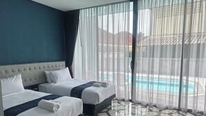 A hotel room with two beds, a large window with sheer curtains, and a view of a swimming pool. - HF Ville (Surat Thani)