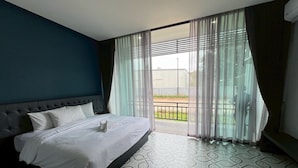 A hotel room with a large bed, a view of the outdoors through sheer curtains, and a patterned floor. - HF Ville (Surat Thani)