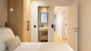 A hotel room with a bed, a bedside table, a wardrobe, and a bathroom visible through an open door. - Elegant Apartment With AC - 3br-6p- Montorgueil (Paris)